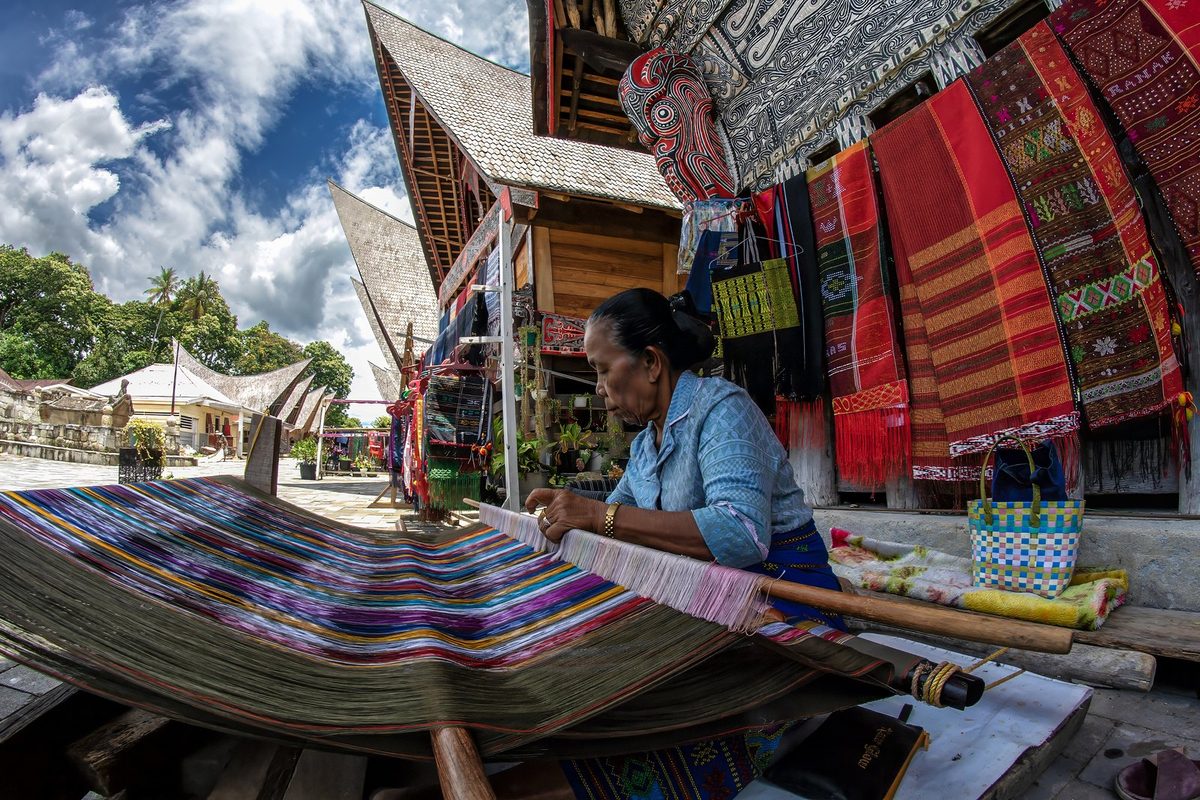 Penenun mengerjakan ulos dengan alat tenun tradisional